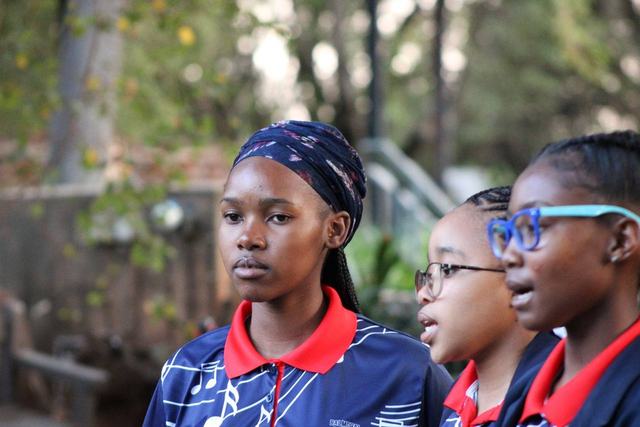 Two learners in school uniform watching an event